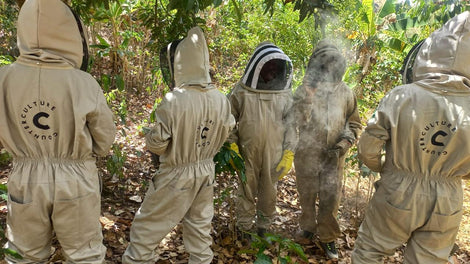 Beekeepers at ASPROCAES in Colombia wearing bee-keeping suits with the Counter Culture Coffee logo on the back. They are working on the apiaries they built after receiving a Seeds grant from Counter Culture.