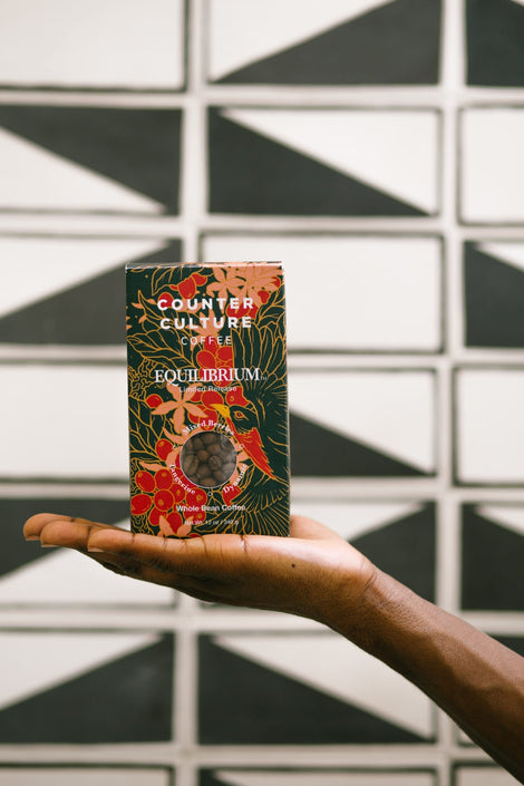 Photo of an outstretched hand holding a box of Equilibrium coffee.