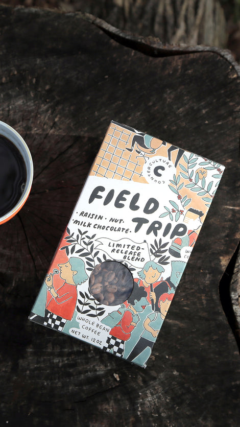 Top down photo of a box of Field Trip coffee on a stump.